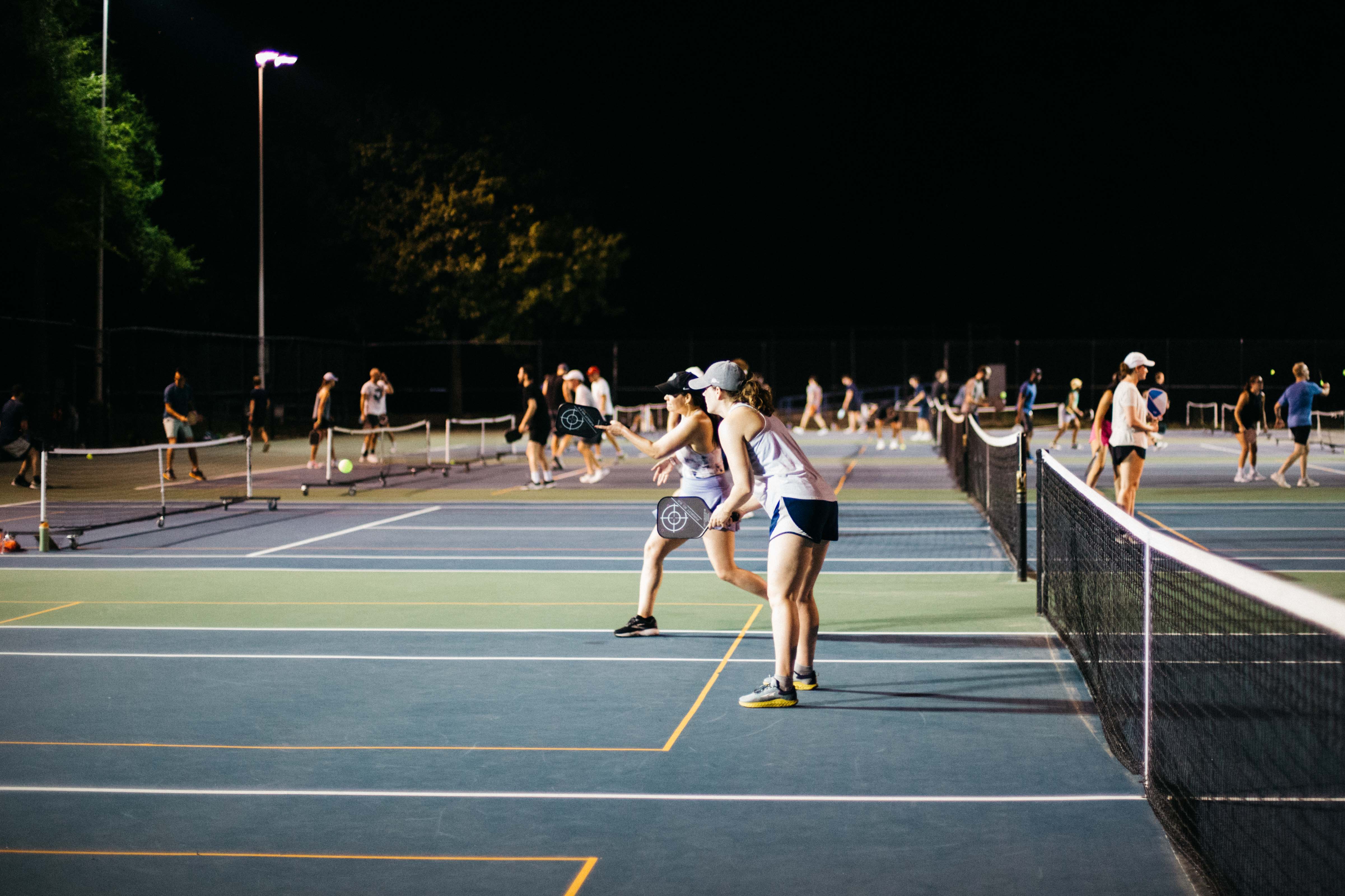 DCPL players competing across multiple courts during an evening ladder league session.